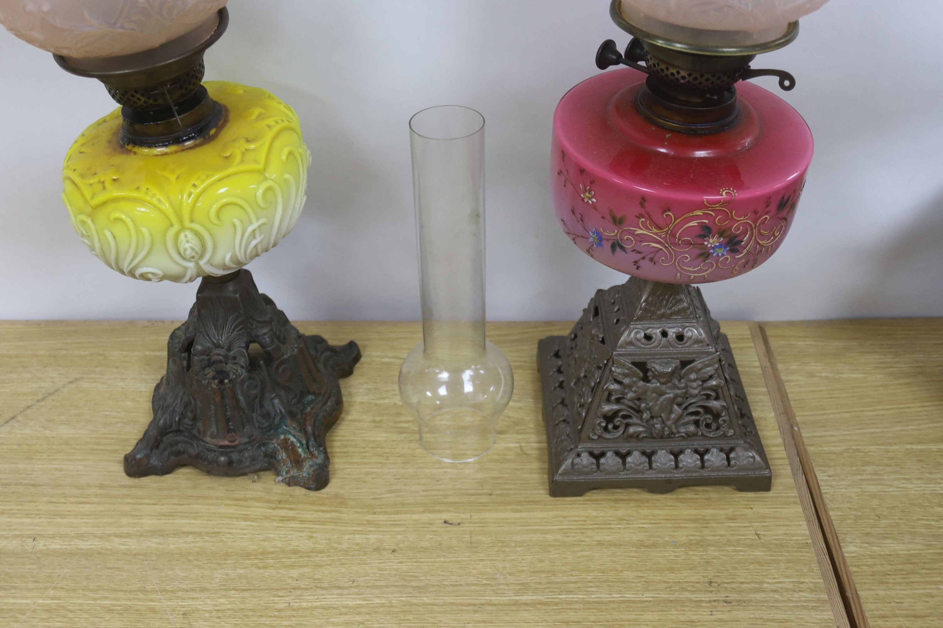 Two late Victorian brass mounted oil lamps with pink and yellow tinted glass reservoirs, tallest 61 cm